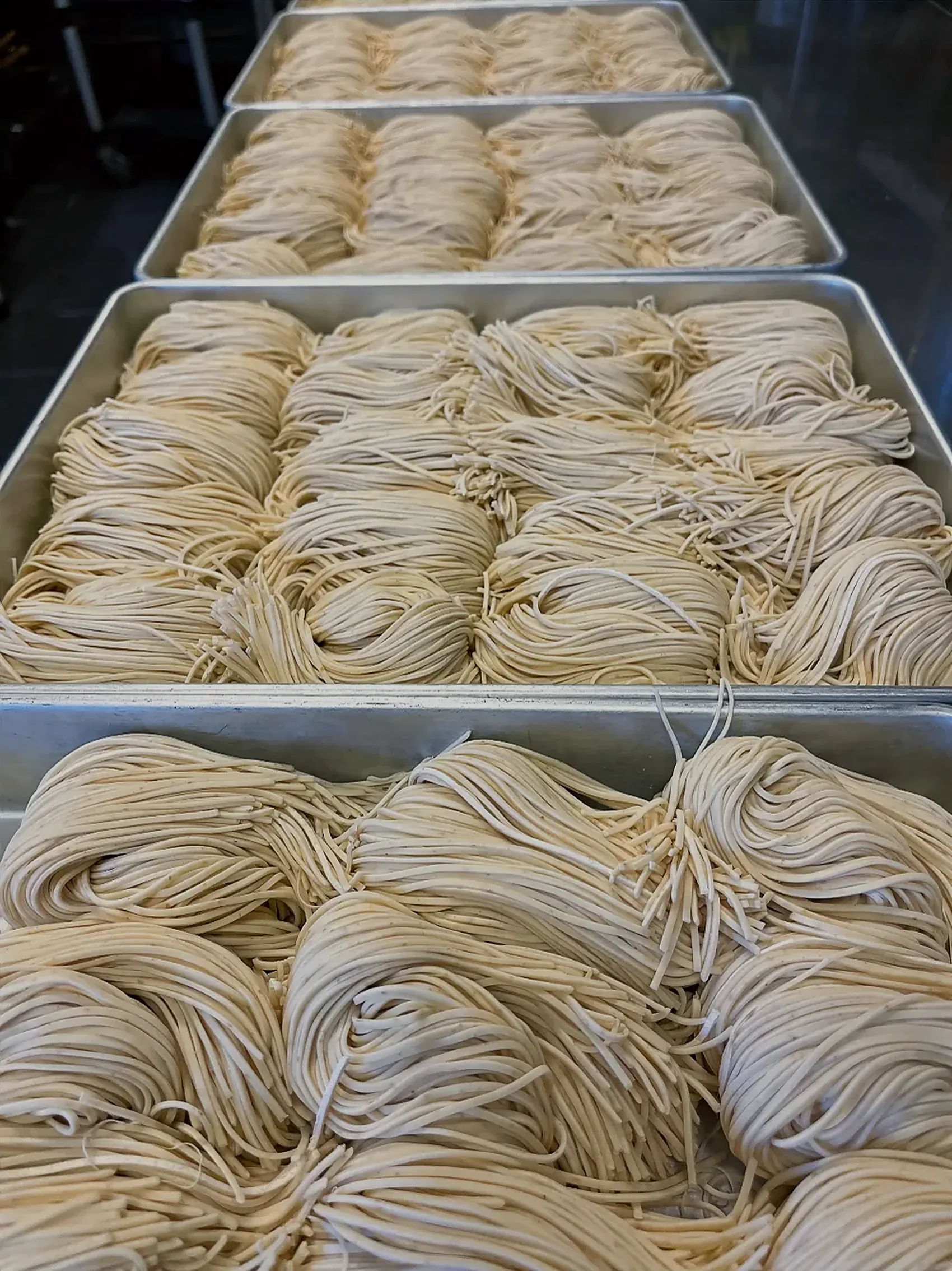 Trays of fresh noodle nests stacked in the kitchen