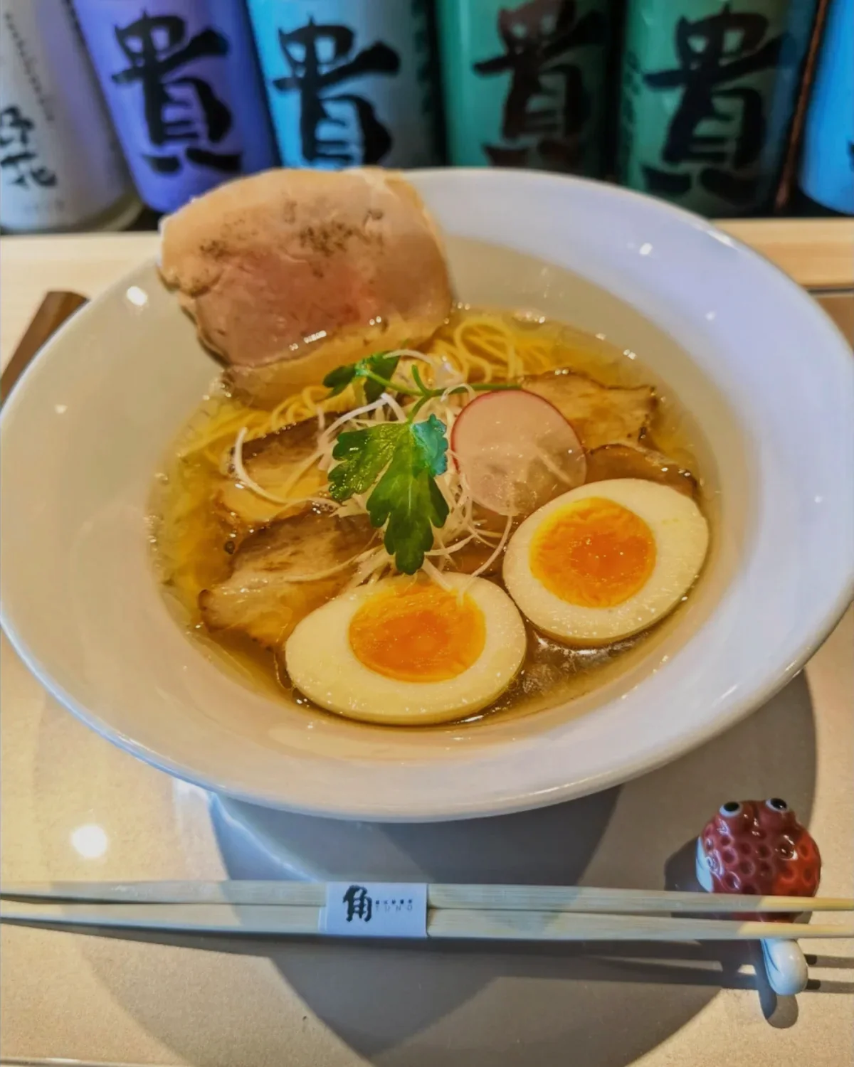 A clear shio ramen with chashu, soft egg, radish and shredded leek