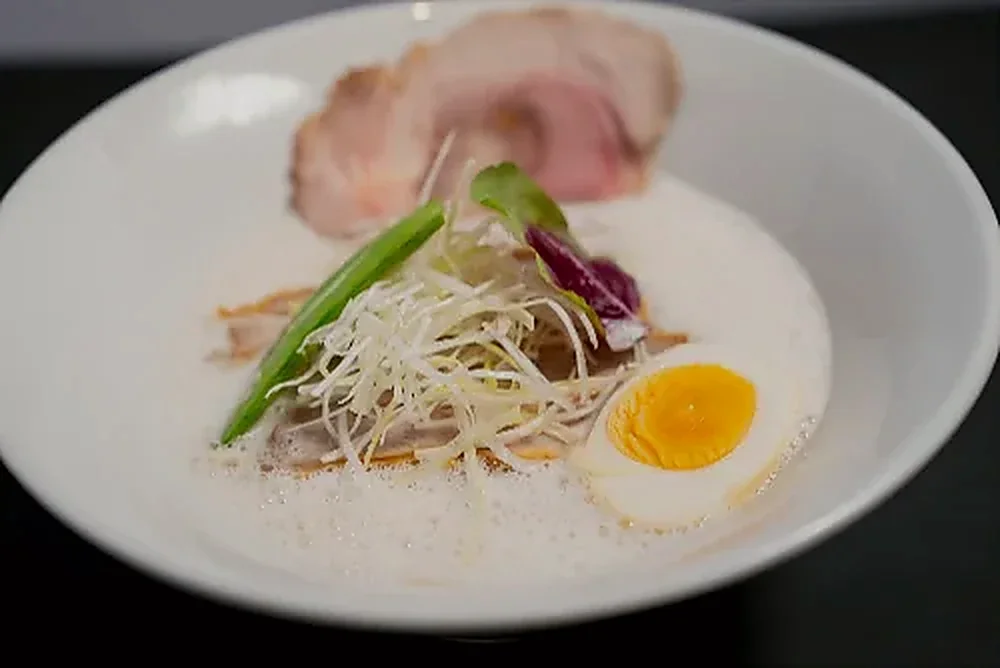 A tonkotsu ramen under a thick cap of foamed broth with chashu and soft egg